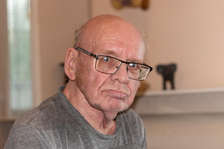 IAn old bald man with glasses. A large portrait. shooting with a frontal flash.