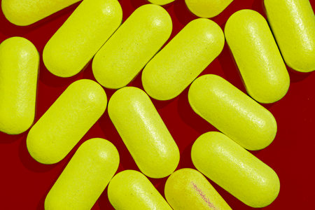 Yellow tablets capsules on dark red background. View from above and isolate.の写真素材