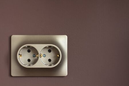 Golden double power socket on a painted brown wall. Standard european electrical connector close-upの写真素材