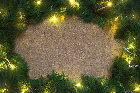 Frame of conifer branches with yellow lights on a wooden board. Christmasの写真素材
