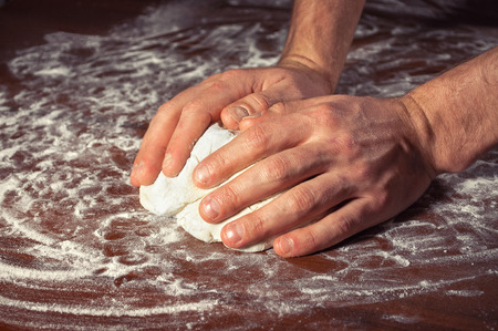 Male hands knead the dough for baking .