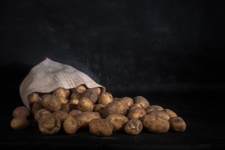 Sack of fresh raw potatoes on black background .の写真素材