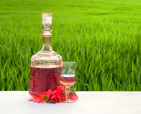 Glass of wine on the table in the field of green grass .の写真素材