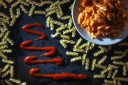 Macaroni in a plate and sauce on the table .の写真素材