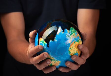 Hands hold the planet Earth. Oil collides on the surface of the planet .