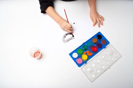 child paints a brush with watercolor honey paintsの写真素材