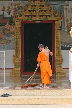 A young monk cleaning outside a templeの写真素材