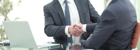 Congratulating with success. Two  men shaking hands while sittinの写真素材