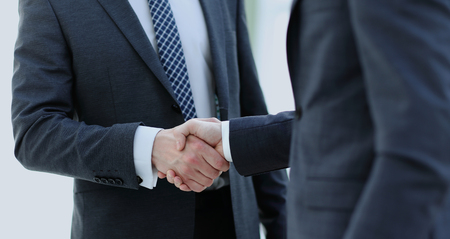 Men shaking hands. Confident businessman shaking hands with each other. Close-up view of the hands of a businessman in the office  in the formal wear.の写真素材