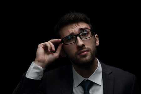 Young businessman looks concentrated isolated on black backgroun