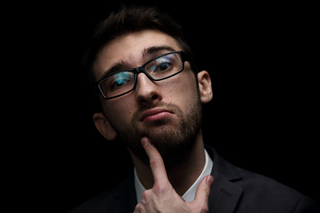 Businessman grimacing isolated on black background.の写真素材