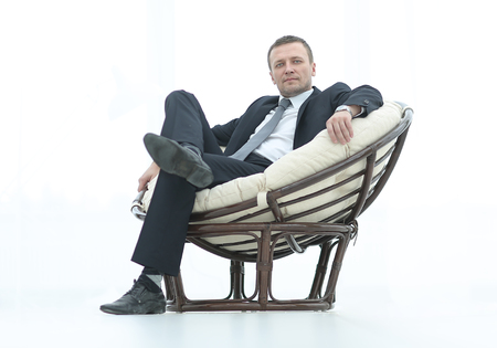 A businessman smiling while sitting in big comfortable chair iso