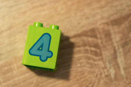 Poznan, Poland - May 12, 2020: Green plastic Lego Duplo block with number 4 on a wooden surface. のeditorial素材