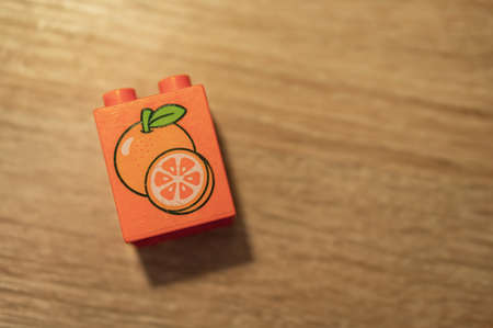 Poznan, Poland - May 12, 2020: Plastic Lego duplo block with orange illustration on a wooden surface.のeditorial素材
