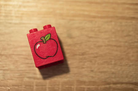 Poznan, Poland - May 12, 2020: Red Lego Duplo block laying on a wooden table in soft focus background. Horizontal aerial view.のeditorial素材