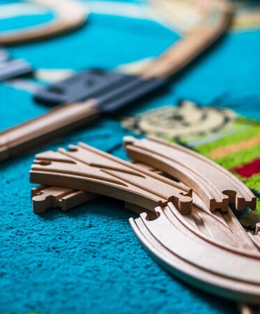 Wooden toy train tracks laying on a carpet floor.の写真素材