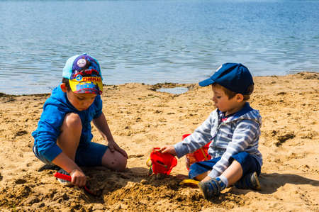 Poznan, Poland - May 9, 2020: Two young kids playing with plastic toys on sand close by the water of the Rusalka lake.のeditorial素材