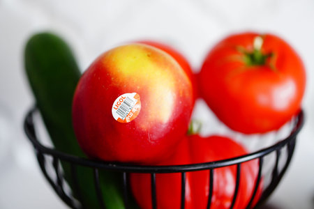 Poznan, Poland - July 2023: A fresh apple with product sticker inside a basketのeditorial素材