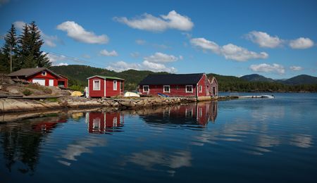Beautiful nordic red shiphouses, boats and cloud reflections in a water. Shot in sunny beautifull day.の写真素材