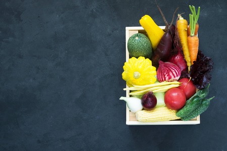 Fresh vegetables in wooden box on a black background. A place for a label.の写真素材