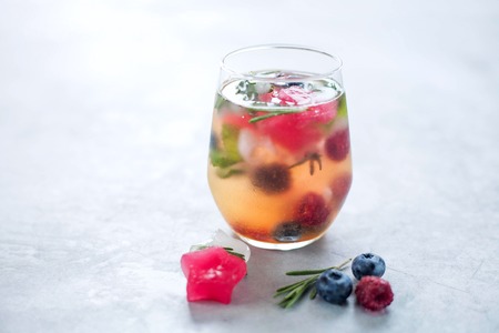 Water with ice cubes with berries and herbs in the form of a star in a glass