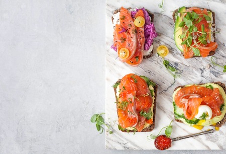 Smorrebrod with salmon on rye bread with vegetables, herbs, microsaint, red caviar and quail eggの写真素材