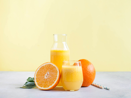 Freshly squeezed orange juice on a yellow background. Copy spaceの写真素材