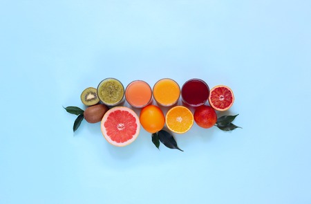 Fresh juices and fruit cut into slices on a turquoise background. The view from the top. Summer,...