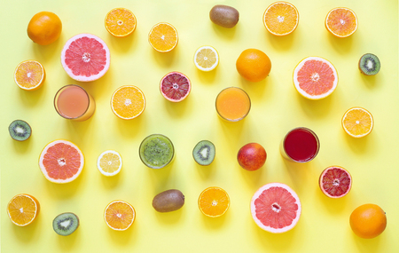 Fresh juices and fruit cut into slices on a yellow backgroundの写真素材