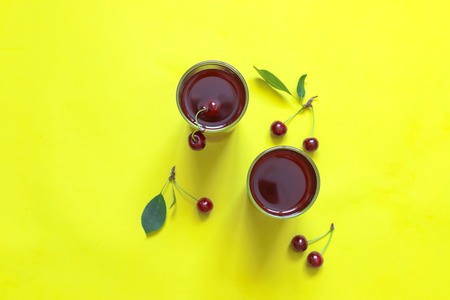Cherry juice with cherry berries on yellow background. Copy spaceの写真素材
