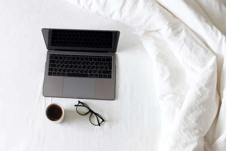 Work at home in quarantine. Laptop on the bed, tea with lemon, tablets, napkins, nasal spray,...