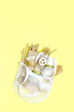 Bag string bag with items made of natural materials. The concept of zero waste. Natural bamboo toothbrush, drinking tube, natural sponge, on a yellow background.  Flat layout, top view, space for copying.の写真素材