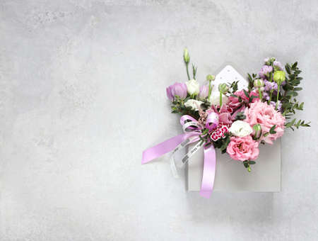 Festive composition, congratulations on the International Women's Day on March 8, Mother's Day, Valentine's Day, wedding day. An original bouquet of flowers made of tulips, orchids, eustoma, eucalyptus sprigs on a gray table.の写真素材