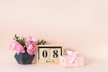 Festive composition, congratulations on the International Women's Day on March 8. A bouquet of flowers in a vase and a gift on the table.の写真素材