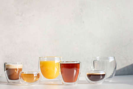 Soft drinks in double-walled glasses. Taken in harsh sunlight on a gray background.の写真素材