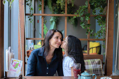 Mom and daughter relax in a cafe, restaurant. They drink tea, juice, mors, communicate and eat salad.の写真素材