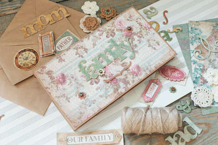 Scrapbooking. On a wooden background, a girl makes a photo album for a family in a vintage style. Top viewの写真素材
