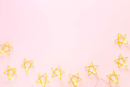 Golden Christmas garland stars on a pink background flat lay, top view. Christmas conceptの写真素材