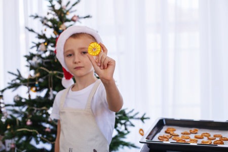The boy takes a baking tray with ready-made orange chips out of the oven. Decorations, decorations for the Christmas tree. orange chips.の写真素材