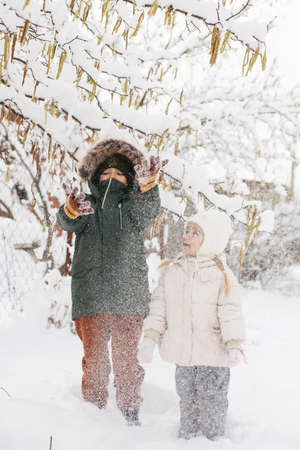 Children boy and girl, brother and sister dressed in warm clothes, playing with snow outside in winterの写真素材