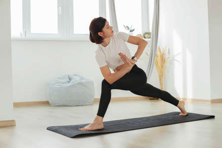 A young brunette girl does yoga, meditates on the floor in the studio, hall.の写真素材