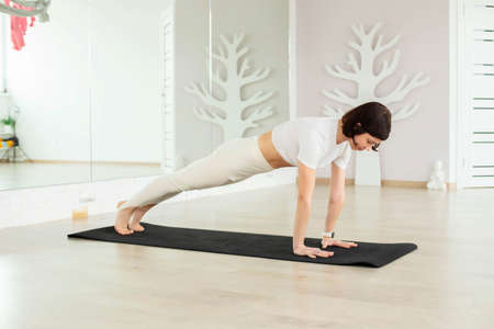 A young brunette girl does yoga, meditates on the floor in the studio, hall.の写真素材