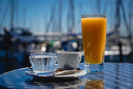 Espresso, water and orange juice as a drink on the bistro table at the port of Heiligenhafen on the...