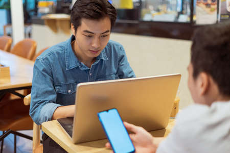 Asian paying man working with colleague, in a coffee shop