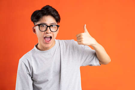 Portrait of young asian man with cryptic expression, isolated on orange background
