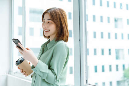 Portrait of young businesswoman standing by the company windowの写真素材