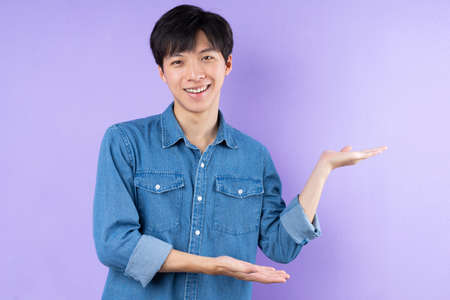 Portrait of Asian man in blue shirt posing on purple backgroundの写真素材