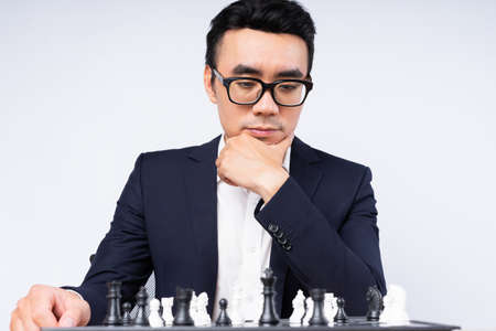Asian businessman is thinking about his next move on the chess boardの写真素材