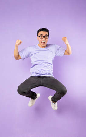 Portrait of a jumping asian man, isolated on purple backgroundの写真素材