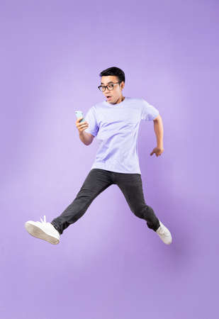 Portrait of a jumping asian man, isolated on purple backgroundの写真素材